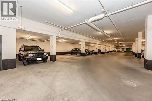Spacious underground parking garage with concrete flooring, multiple support columns, and overhead fluorescent lighting - 85 Duke Street W Unit# 507, Kitchener, ON - Indoor Photo Showing Garage