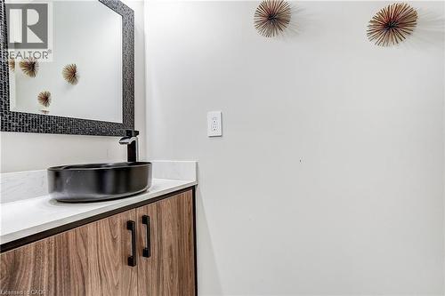 Contemporary vanity featuring a vessel sink with a matte black faucet, wood-finish cabinetry, and a light-toned countertop - 1264 Kane Road, Mississauga, ON - Indoor