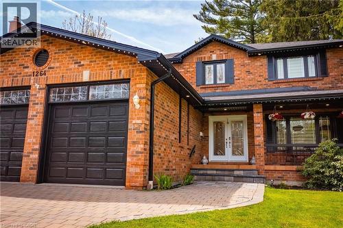 Brick facade residence featuring a two-car garage with panel doors, a patterned paver driveway, and a covered entry with double glass panel doors - 1264 Kane Road, Mississauga, ON - Outdoor With Deck Patio Veranda