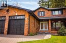 Brick facade residence featuring a two-car garage with panel doors, a patterned paver driveway, and a covered entry with double glass panel doors - 1264 Kane Road, Mississauga, ON  - Outdoor With Deck Patio Veranda 