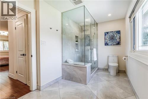 Glass-enclosed shower with a built-in bench and recessed shelving, complemented by large format floor tiles and a white toilet - 1264 Kane Road, Mississauga, ON - Indoor Photo Showing Bathroom