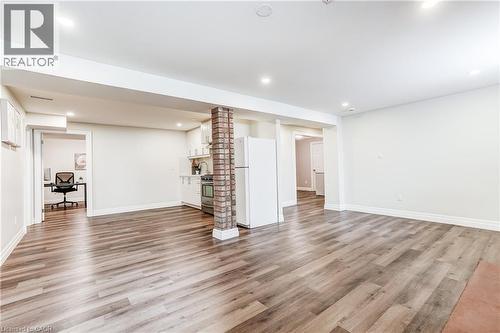 Open-concept living space featuring wood-finish flooring, recessed lighting, and a partial kitchen with white cabinetry and a full-size refrigerator - 1264 Kane Road, Mississauga, ON - Indoor