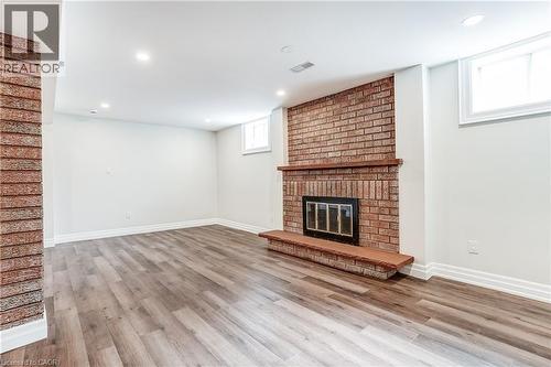 Spacious room featuring a brick fireplace with a wood mantle, wood-finish flooring, recessed lighting, and white baseboards - 1264 Kane Road, Mississauga, ON - Indoor With Fireplace