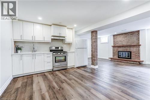 Full kitchen featuring white cabinetry, stainless steel range, and quartz-finish countertops - 1264 Kane Road, Mississauga, ON - Indoor With Fireplace