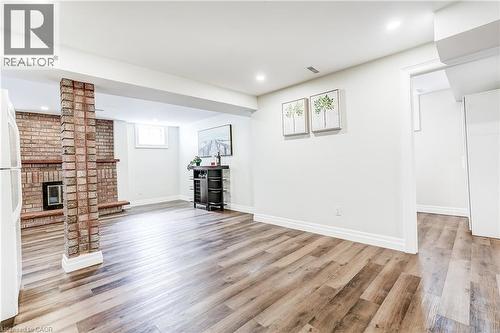 Spacious room featuring wood-finish flooring, a brick-faced fireplace, a brick column, and recessed lighting - 1264 Kane Road, Mississauga, ON - Indoor With Fireplace