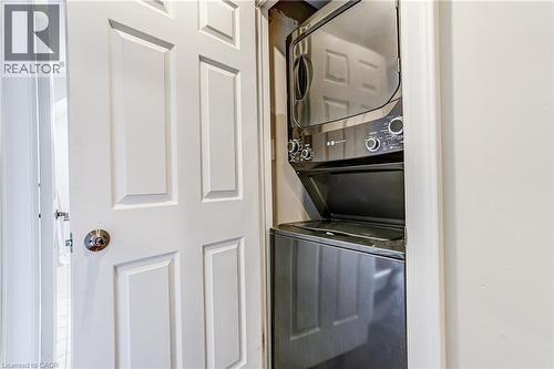 Space-saving stacked washer and dryer unit with dark finishes - 1264 Kane Road, Mississauga, ON - Indoor Photo Showing Laundry Room