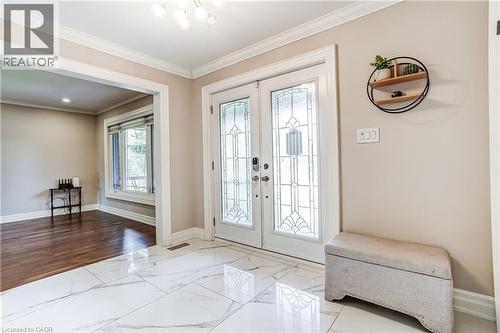 Grand entryway featuring double doors with decorative glass panels, leading to a spacious room with wood-finish flooring and a large bay window - 1264 Kane Road, Mississauga, ON - Indoor Photo Showing Other Room