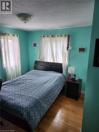 Bedroom featuring wood-finish flooring and two windows with white sheer curtains - 1126 Copper Leaf Crescent, Kitchener, ON - Indoor Photo Showing Bedroom