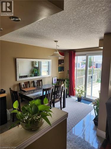 Dining area with a pendant light fixture, featuring a sliding glass door to the exterior, wood-finish dining chairs, and a large wall mirror - 1126 Copper Leaf Crescent, Kitchener, ON - Indoor