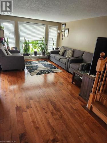 Living area featuring wood-finish flooring, a neutral wall palette, and expansive windows with horizontal blinds - 1126 Copper Leaf Crescent, Kitchener, ON - Indoor Photo Showing Living Room