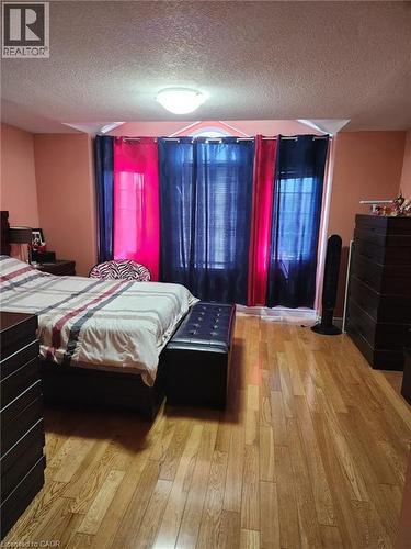 Spacious room featuring wood-finish flooring, a contemporary ceiling light fixture, and a window arrangement with an arched transom - 1126 Copper Leaf Crescent, Kitchener, ON - Indoor Photo Showing Bedroom