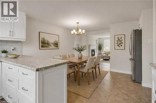 White kitchen cabinetry with stainless steel hardware, stone-finish countertops, subway tile backsplash, and a stainless steel refrigerator - 22 Blackhorne Crescent, Kitchener, ON - Indoor