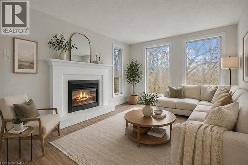 Living space featuring a white mantel fireplace with a black insert, wood-finish flooring, and multiple windows - 22 Blackhorne Crescent, Kitchener, ON - Indoor Photo Showing Living Room With Fireplace