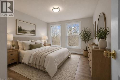 Bedroom featuring two large windows, wood-finish flooring, a light-colored area rug, a flush-mount ceiling light, and light-toned walls - 22 Blackhorne Crescent, Kitchener, ON - Indoor Photo Showing Bedroom