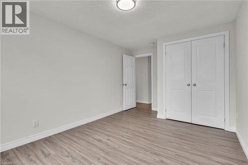 Interior room featuring light grey walls, wood-finish flooring, white trim, and a white bi-fold closet door - 22 Blackhorne Crescent, Kitchener, ON - Indoor Photo Showing Other Room