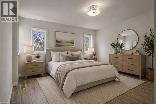 Spacious room featuring wood-finish flooring, two windows with white trim, a decorative flush-mount ceiling light, and light-toned walls - 22 Blackhorne Crescent, Kitchener, ON - Indoor Photo Showing Bedroom