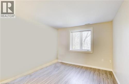 Bright interior space featuring a window with white trim, light neutral wall paint, white baseboards, and wood-finish flooring - 22 Blackhorne Crescent, Kitchener, ON - Indoor Photo Showing Other Room