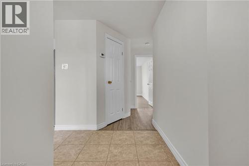 Hallway with tiled flooring transitioning to wood-finish flooring, featuring white interior doors and light-toned walls - 22 Blackhorne Crescent, Kitchener, ON - Indoor Photo Showing Other Room
