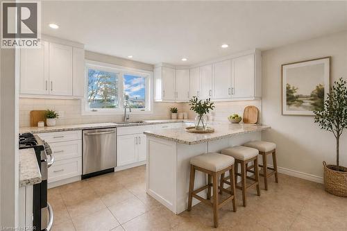 Kitchen featuring a functional island with seating, white shaker-style cabinetry, stainless steel appliances, light-toned granite countertops, and a subway tile backsplash - 22 Blackhorne Crescent, Kitchener, ON - Indoor Photo Showing Kitchen