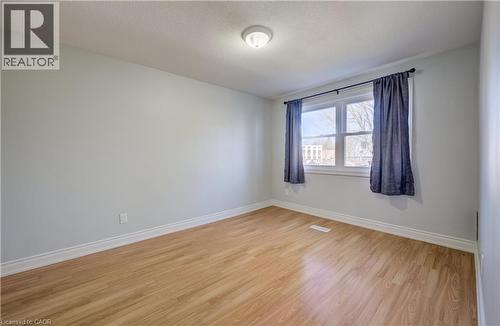 Bright room featuring wood-finish flooring, light-toned wall paint, white trim, and a window with natural light - 80 Heiman Street, Kitchener, ON - Indoor Photo Showing Other Room