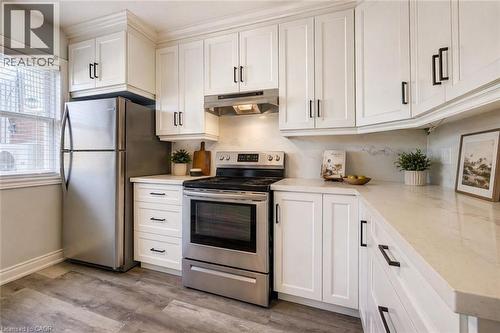 Modern kitchen featuring white shaker cabinetry, stainless steel appliances, light-toned countertops, and wood-finish flooring - 80 Heiman Street, Kitchener, ON - Indoor Photo Showing Kitchen