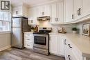 Modern kitchen featuring white shaker cabinetry, stainless steel appliances, light-toned countertops, and wood-finish flooring - 80 Heiman Street, Kitchener, ON  - Indoor Photo Showing Kitchen 