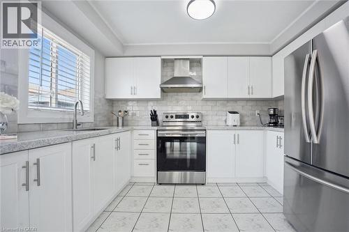 Modern kitchen featuring white cabinetry, light-toned countertops, a subway tile backsplash, stainless steel appliances, and tiled flooring - 5449 Rochelle Way, Mississauga, ON - Indoor Photo Showing Kitchen With Stainless Steel Kitchen