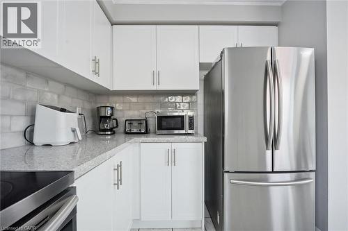 Kitchen featuring white cabinetry, light-toned countertops, a full stainless steel refrigerator, and a light-toned subway tile backsplash - 5449 Rochelle Way, Mississauga, ON - Indoor Photo Showing Kitchen With Stainless Steel Kitchen With Upgraded Kitchen