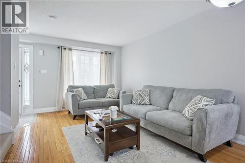 Light-filled living area featuring wood-finish flooring, neutral wall tones, and a decorative front entry door with transom window - 5449 Rochelle Way, Mississauga, ON - Indoor Photo Showing Living Room