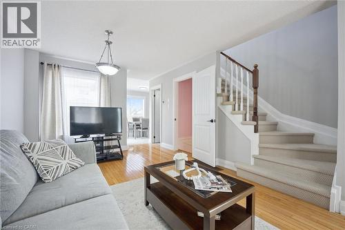 Hardwood-style flooring extends throughout the living area, complemented by a contemporary semi-flush mount light fixture - 5449 Rochelle Way, Mississauga, ON - Indoor Photo Showing Living Room