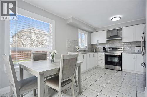 Bright kitchen featuring white cabinetry, stainless steel appliances, a subway tile backsplash, and light-toned tile flooring - 5449 Rochelle Way, Mississauga, ON - Indoor