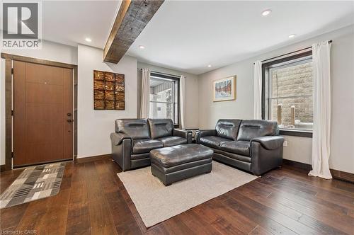 Living area featuring wood-finish flooring, recessed lighting, and a prominent exposed wood ceiling beam - 838 Moore Street, Cambridge, ON - Indoor Photo Showing Living Room