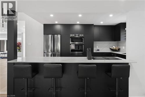 Kitchen with dark cabinetry, appliances with stainless steel finishes, a breakfast bar area, light stone countertops, and recessed lighting - 17 Clearview Drive, Hamilton, ON - Indoor Photo Showing Kitchen With Upgraded Kitchen