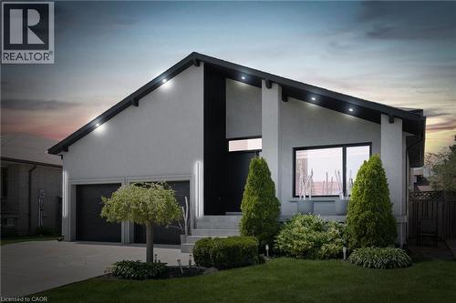 Property exterior at dusk with driveway, stucco siding, and an attached garage - 17 Clearview Drive, Hamilton, ON - Outdoor