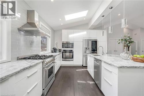 Bright kitchen with white high-gloss cabinetry, marble-patterned countertops, and dark wood-finish flooring - 2123 Deyncourt Drive, Burlington, ON - Indoor Photo Showing Kitchen With Upgraded Kitchen