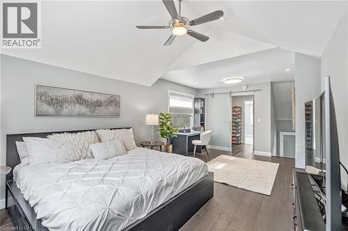 Vaulted ceilings with a ceiling fan, dark wood-finish flooring, a desk area with built-in shelving, and a barn door entry - 2123 Deyncourt Drive, Burlington, ON - Indoor Photo Showing Bedroom