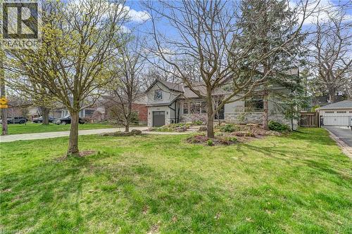 Light gray exterior with stone detailing, a prominent gabled roofline, and a driveway leading to an integrated garage - 2123 Deyncourt Drive, Burlington, ON - Outdoor