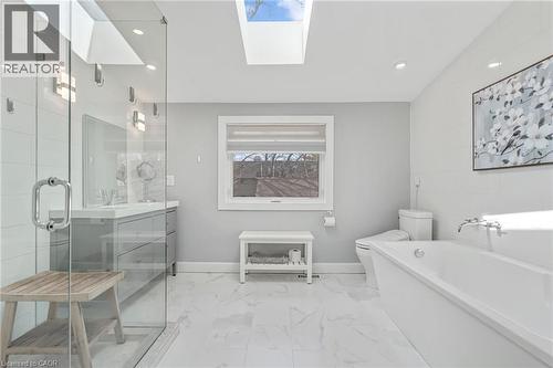 Contemporary bathroom featuring a freestanding tub, glass-enclosed shower, dual vanity with undermount sinks, skylights, and large format marble-look floor tiles - 2123 Deyncourt Drive, Burlington, ON - Indoor Photo Showing Bathroom