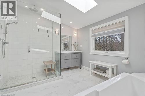 Contemporary bathroom featuring a glass-enclosed shower with a rainfall showerhead, a large soaking tub, a vanity with ample storage, and a skylight - 2123 Deyncourt Drive, Burlington, ON - Indoor Photo Showing Bathroom