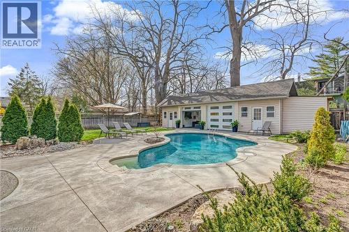 Freeform swimming pool with integrated spa, surrounded by extensive concrete decking - 2123 Deyncourt Drive, Burlington, ON - Outdoor With In Ground Pool