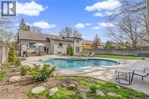Expansive backyard featuring a large in-ground swimming pool with integrated steps, surrounded by a concrete patio - 2123 Deyncourt Drive, Burlington, ON - Outdoor With In Ground Pool With Backyard