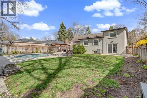 Rear yard featuring a swimming pool with concrete decking, a stucco exterior, and a wood fence enclosure - 2123 Deyncourt Drive, Burlington, ON - Outdoor With In Ground Pool