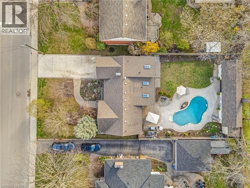 Exterior grounds featuring a freeform pool with integrated patio, a separate lawn area, and a paved driveway - 2123 Deyncourt Drive, Burlington, ON - Outdoor With In Ground Pool