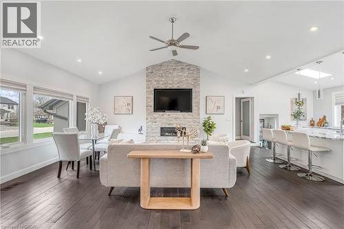 Open-concept living space featuring wood-finish flooring, a stone-clad fireplace with a mounted television, and a vaulted ceiling with recessed lighting - 2123 Deyncourt Drive, Burlington, ON - Indoor Photo Showing Dining Room