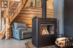Freestanding black wood-burning stove with glass door, log-style interior, and integrated chimney pipe - 