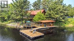 Waterfront property featuring a main residence with a red tile roof, a log-style boathouse, and extensive decking - 
