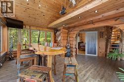 Expansive sunroom featuring log and plank wood walls, wood-finish flooring, recessed lighting, and large windows - 