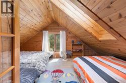 Vaulted wood-paneled ceilings and walls define this room, featuring light-colored carpeting, a multi-pane window with white curtains, and a built-in wood-paneled dormer - 