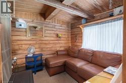 Interior space featuring natural wood log walls, a wood-finish vaulted ceiling with exposed beams, and light-colored carpet flooring - 