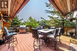 Expansive outdoor deck featuring wood-finish flooring, a wood-paneled ceiling, and a log-style exterior wall - 